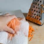 squeezing moisture from freshly grated carrots for mini carrot cakes