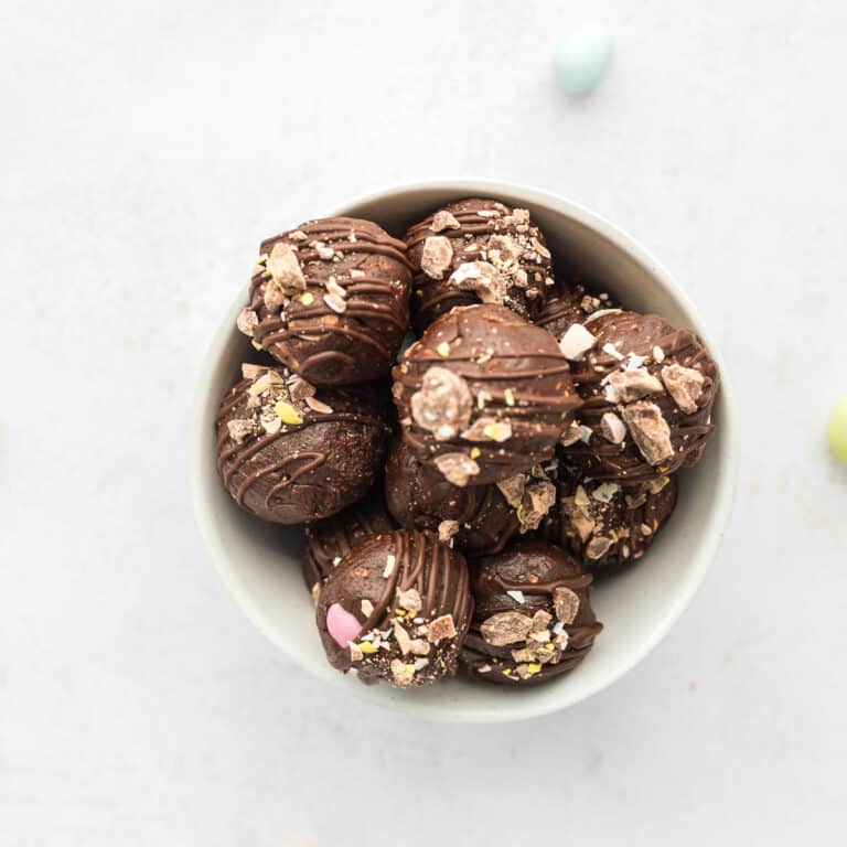 Overhead shot of Mini egg brownie batter energy balls made with chocolate protein powder and chopped mini eggs, in white bowl