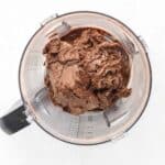 Blending dates, protein powder, cocoa powder, and nut butter in a food processor