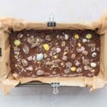 Melted chocolate layer and crushed mini eggs on top of mini egg cookie dough protein bars