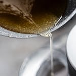 hot syrup being poured from a pan into mixer with gelatin for marshmallows