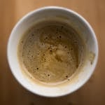 Close-up of espresso mixture for tiramisu in a white cup on a wooden table.