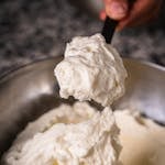 Delicious creamy ricotta and mascarpone cheese being mixed in a stainless steel bowl.