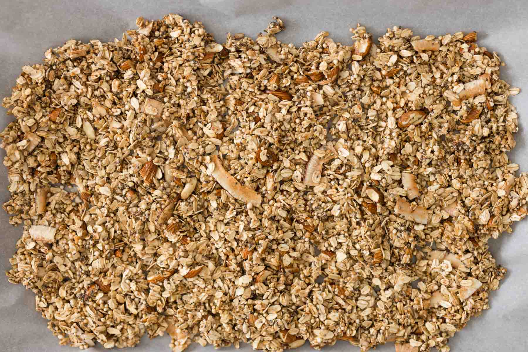 Easy Homemade Healthy Granola pressed down into parchment-lined baking sheet