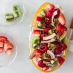papaya breakfast bowl with yogurt, berries, kiwis, coconut, and granola