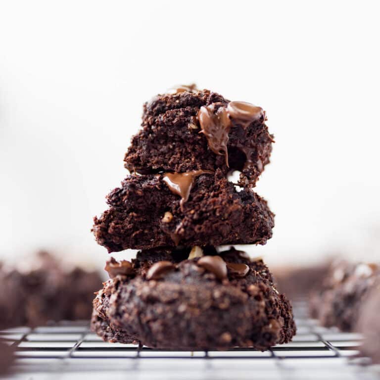 Stack of 3 fudgy banana chocolate cookies on black cooling rack