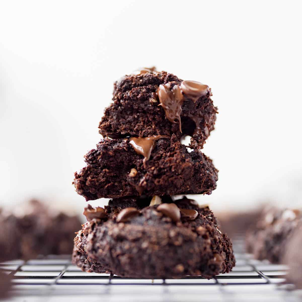 Stack of 3 fudgy banana chocolate cookies on black cooling rack