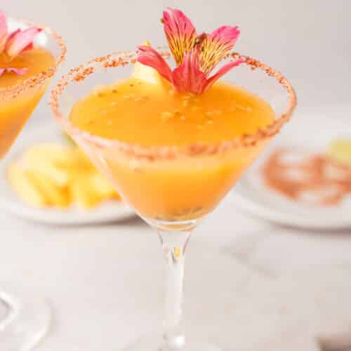 Passion fruit Mango mocktails in Tajín-rimmed glasses with lime, passion fruit, and mango garnish