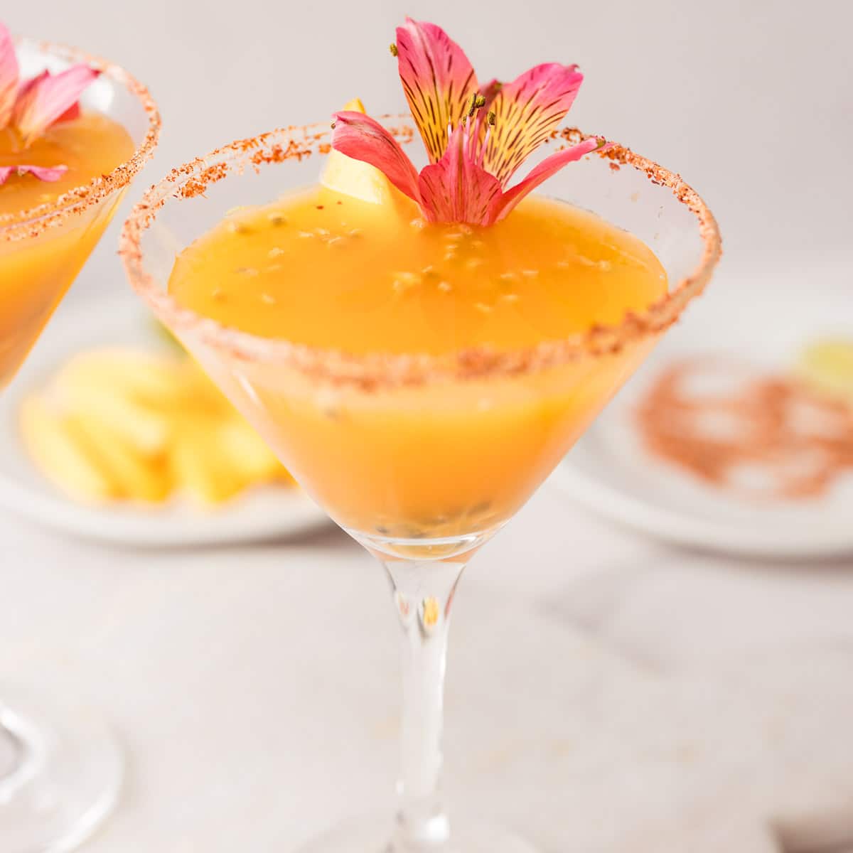 Passion fruit Mango mocktails in Tajín-rimmed glasses with lime, passion fruit, and mango garnish