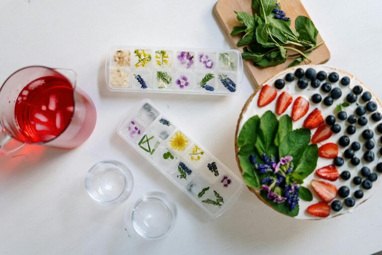 floral ice cubes, fresh berries, and mint on a flatlay.