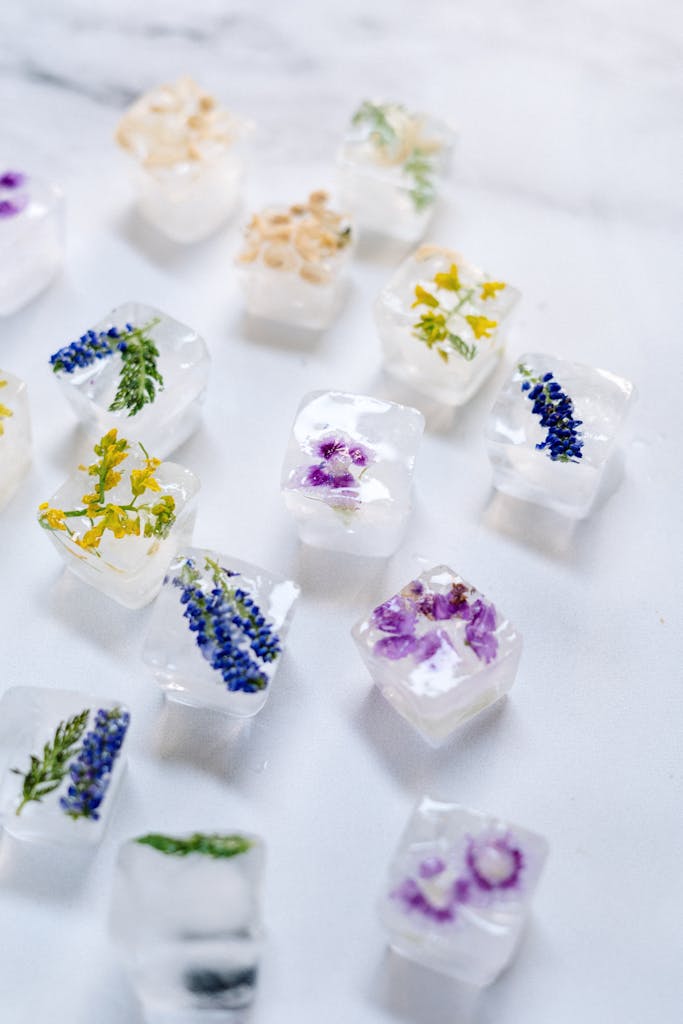 Close-up view of floral ice cubes with embedded flowers on a marble surface, perfect for refreshing drinks.