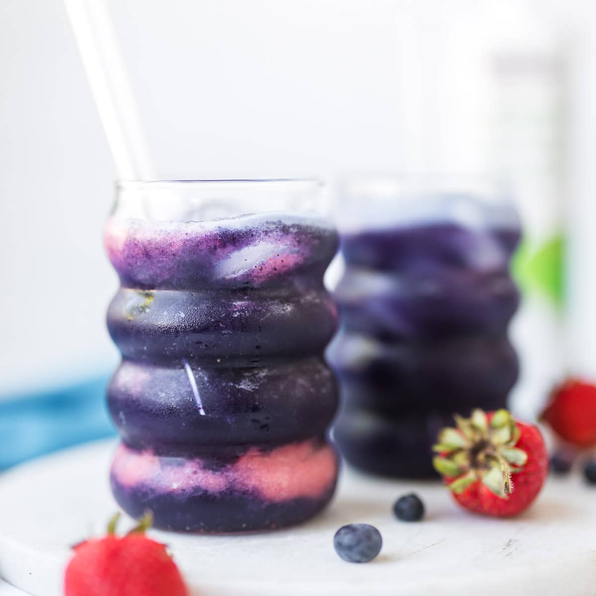 Healthy strawberry blueberry electrolyte mocktail made with coconut water, fresh strawberries, blueberries, and ice in a clear glass.