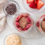 Half of the blended chocolate overnight oats poured into a jar and topped with strawberries.
