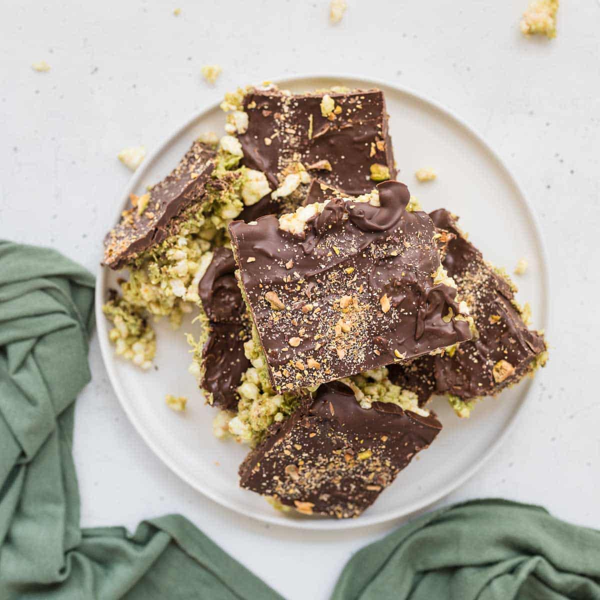 Dubai Chocolate Rice Cake Bars topped with chocolate and crushed pistachios, sliced into squares on white plate