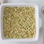 Crushed rice cakes mixed with pistachio cream, tahini, and honey and pressed down into 8x8x pan for the base of Dubai Chocolate Rice Cake Bars.