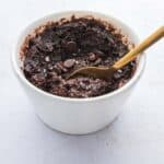 cooked fudgy protein brownie mug cake with gold spoon taking a scoop of gooey center