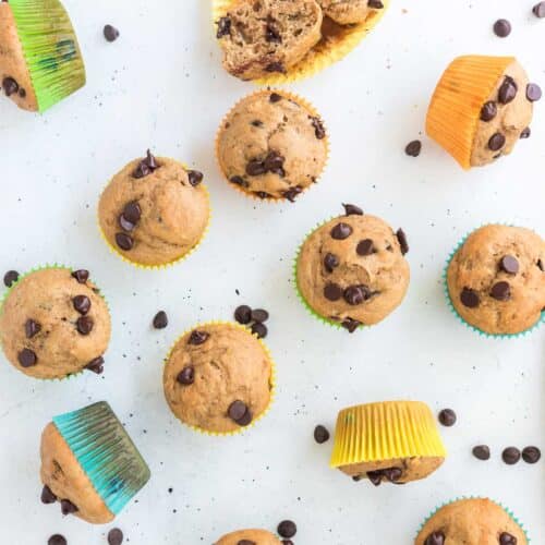 Healthy Greek Yogurt Chocolate Chip Muffins in colorful wrappers on white surface