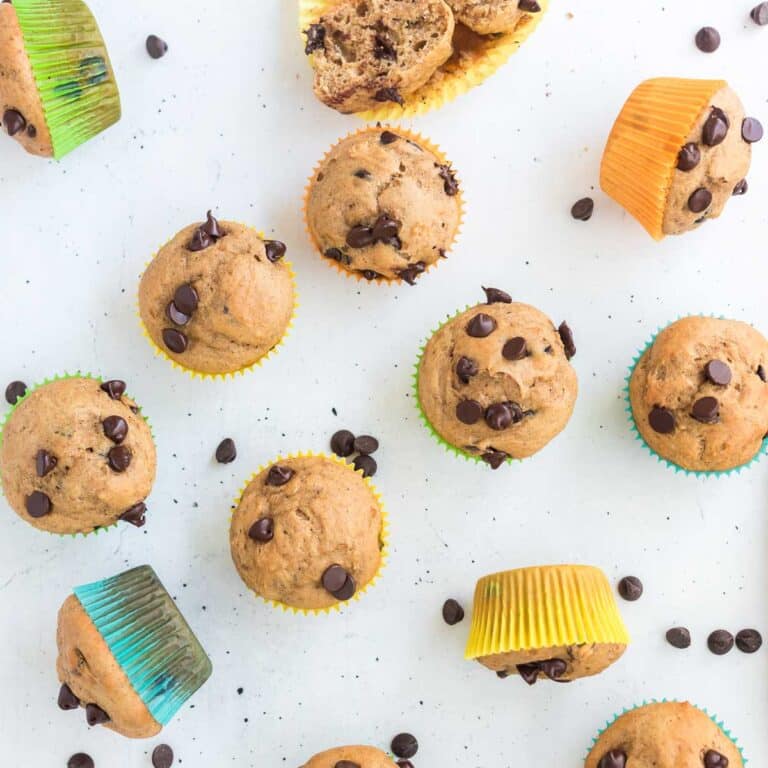 Healthy Greek Yogurt Chocolate Chip Muffins in colorful wrappers on white surface