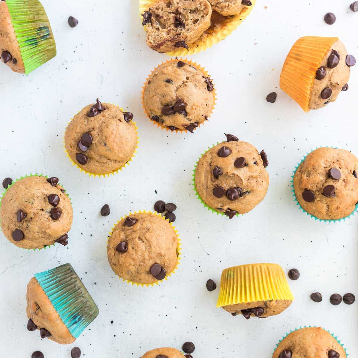 Healthy Greek Yogurt Chocolate Chip Muffins in colorful wrappers on white surface