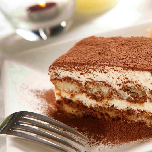 A close-up of a delicious tiramisu dessert dusted with cocoa powder, ready to enjoy.