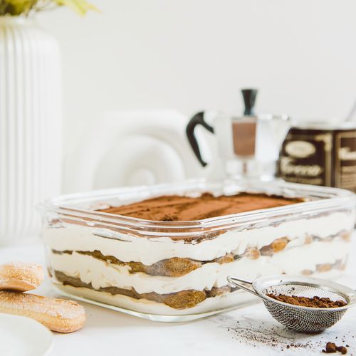 Beautiful layered tiramisu dessert with a coffee-focused setup, styled indoors
