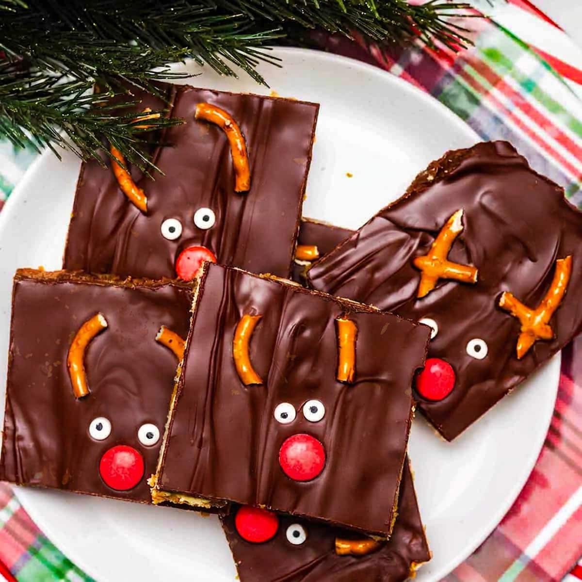 Christmas Toffee pieces on a plate with cute Reindeer faces made out of candy and pretzel pieces