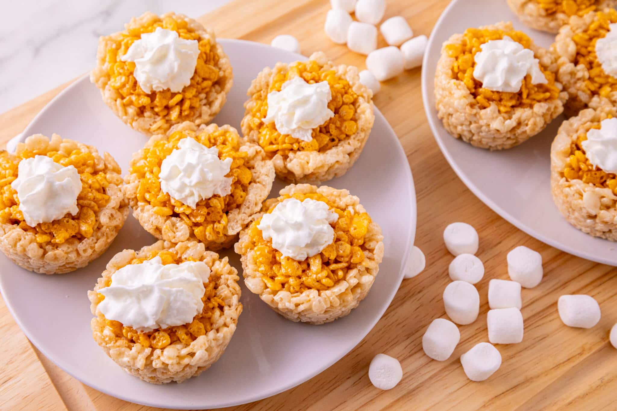 Pumpkin Rice Krispie treats shaped like mini pumpkin pies topped with whipped cream