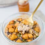 Spoonful of thick and creamy pumpkin cheesecake overnight oats topped with cooked apples, pumpkin seeds, walnuts, cacao nibs.