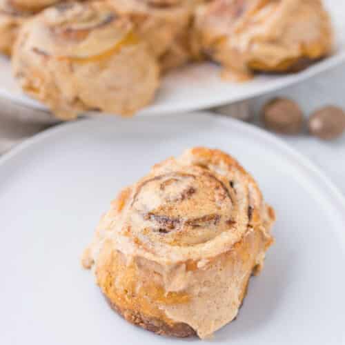Pumpkin cinnamon roll with creamy cinnamon frosting on a plate