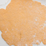 Pumpkin cinnamon roll dough rolled into a rectangle on a lightly floured surface